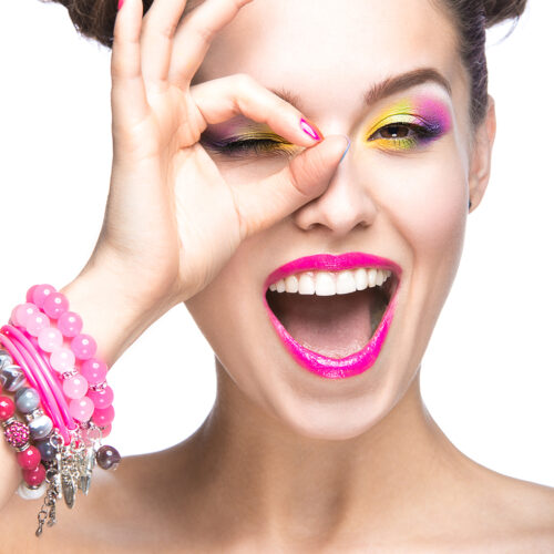 Beautiful girl in pink sunglasses with bright makeup and colorful nails. Beauty face. Picture taken in the studio on a white background.
