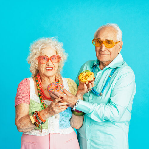 Beautiful senior old couple wearing fancy party clothes acting in studio on a colored background. Beautiful senior old couple wearing fancy party clothes acting in studio on a colored background. Conceptual image about third age and seniority, old people feeling young inside.