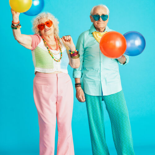 Beautiful senior old couple wearing fancy party clothes acting in studio on a colored background. Beautiful senior old couple wearing fancy party clothes acting in studio on a colored background. Conceptual image about third age and seniority, old people feeling young inside.