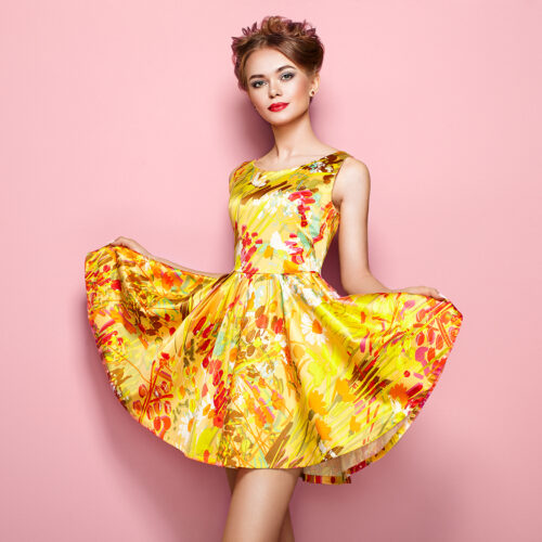 Portrait of Fashion Young woman in Floral Dress. Female model in Stylish Summer Outfit. Girl Posing on a Pink Background. Stylish Hairstyle. Fashion Photo. Blonde Lady