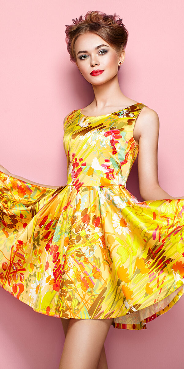 Portrait of Fashion Young woman in Floral Dress. Female model in Stylish Summer Outfit. Girl Posing on a Pink Background. Stylish Hairstyle. Fashion Photo. Blonde Lady