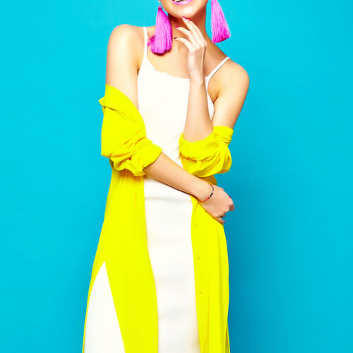 portrait of cheerful fashion hipster girl in casual colorful vivid hipster yellow summer clothes on blue background