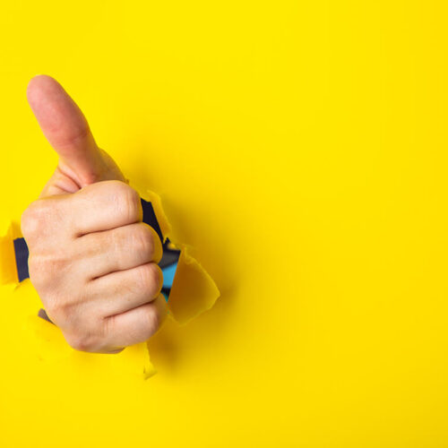 hand-showing-a-thumb-up-sign-through-a-ripped-hole-2023-11-27-05-11-12-utc