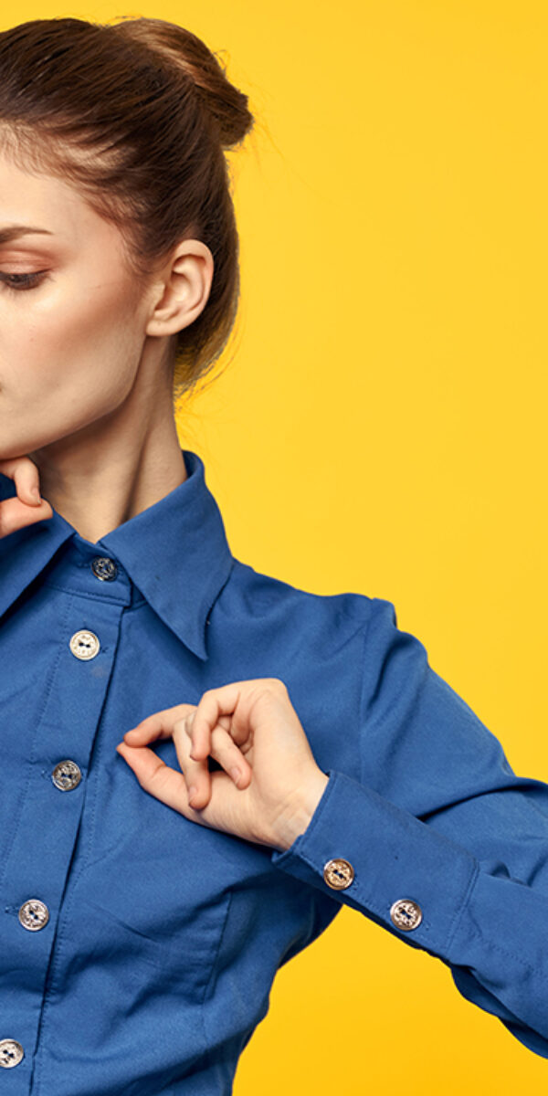Portrait of a woman in a blue shirt with bright makeup red lips yellow background cropped view. High quality photo