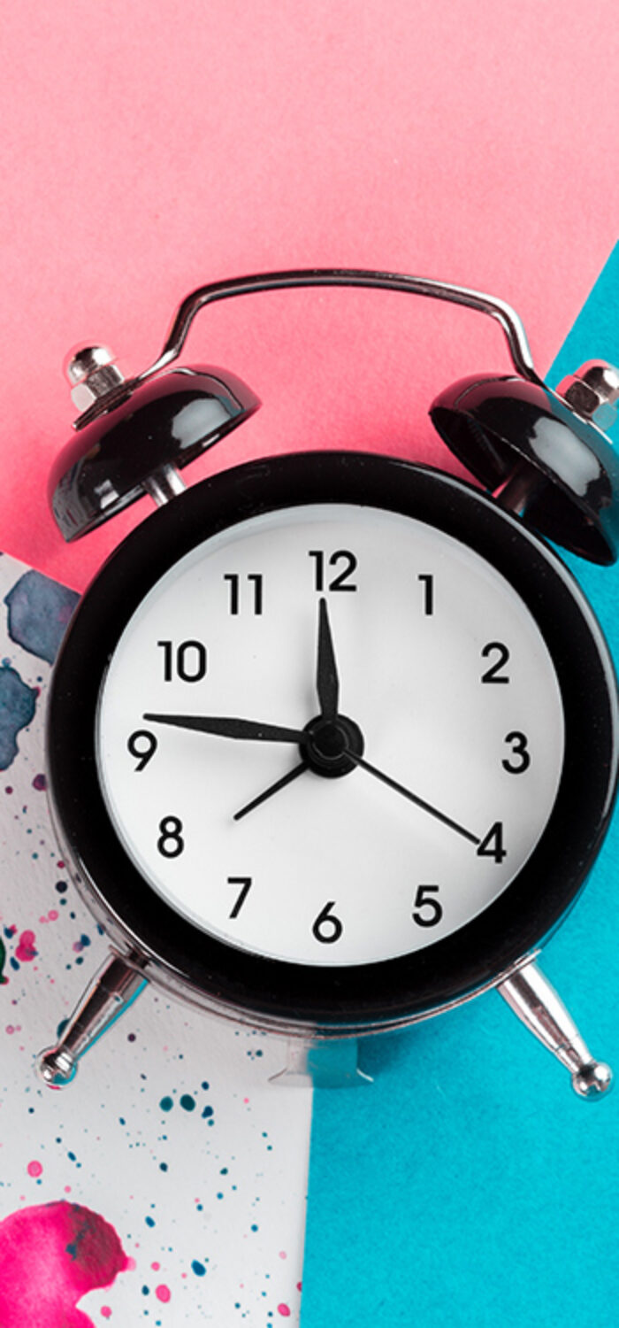 Vintage alarm clock on a creative colorful background with paint sprinkles
