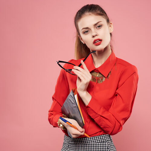 woman in red shirt and glasses documents in hands of secretary pink background woman in red shirt and glasses documents in hands of secretary pink background. High quality photo